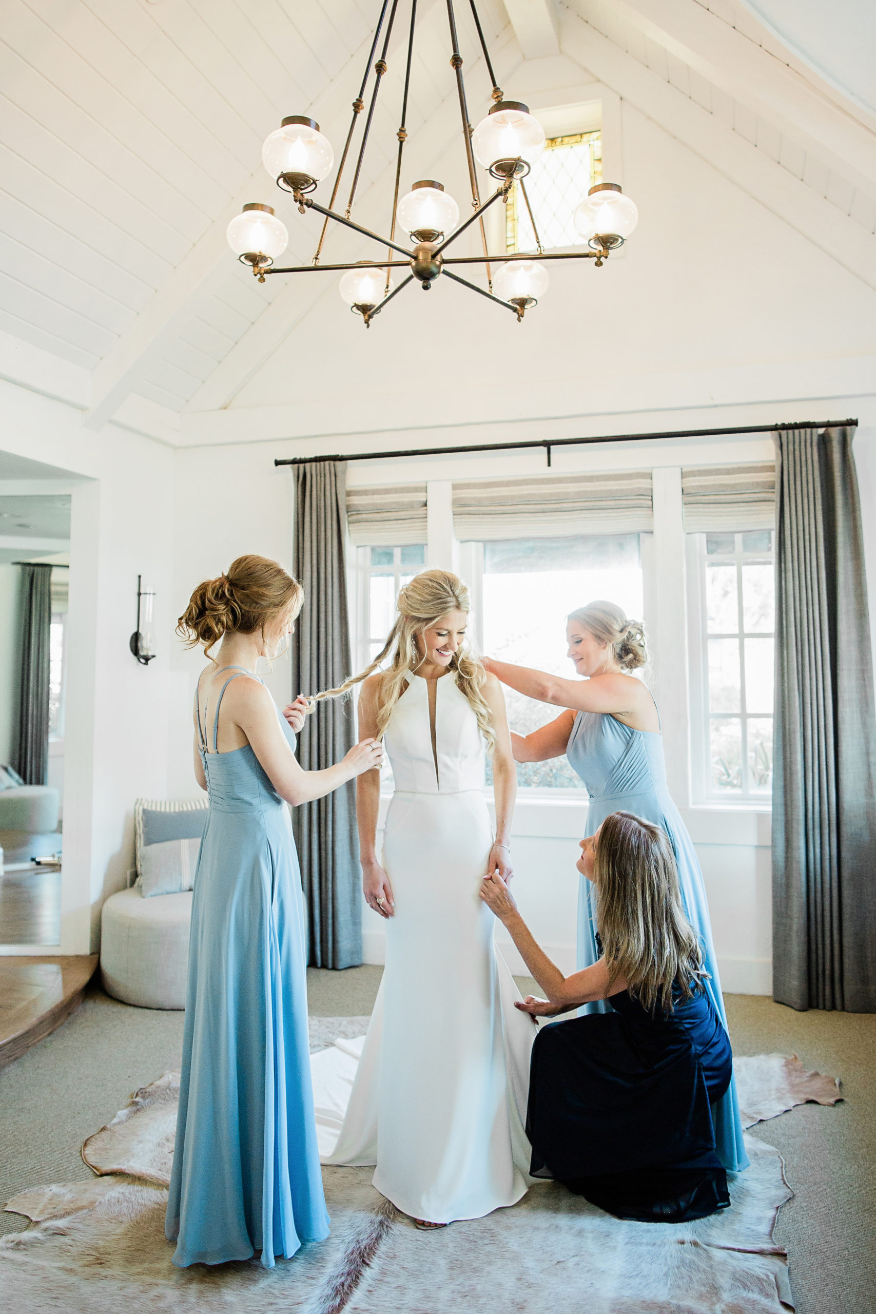 Bride getting her dress put on with the bridesmaids helping her get dressed
