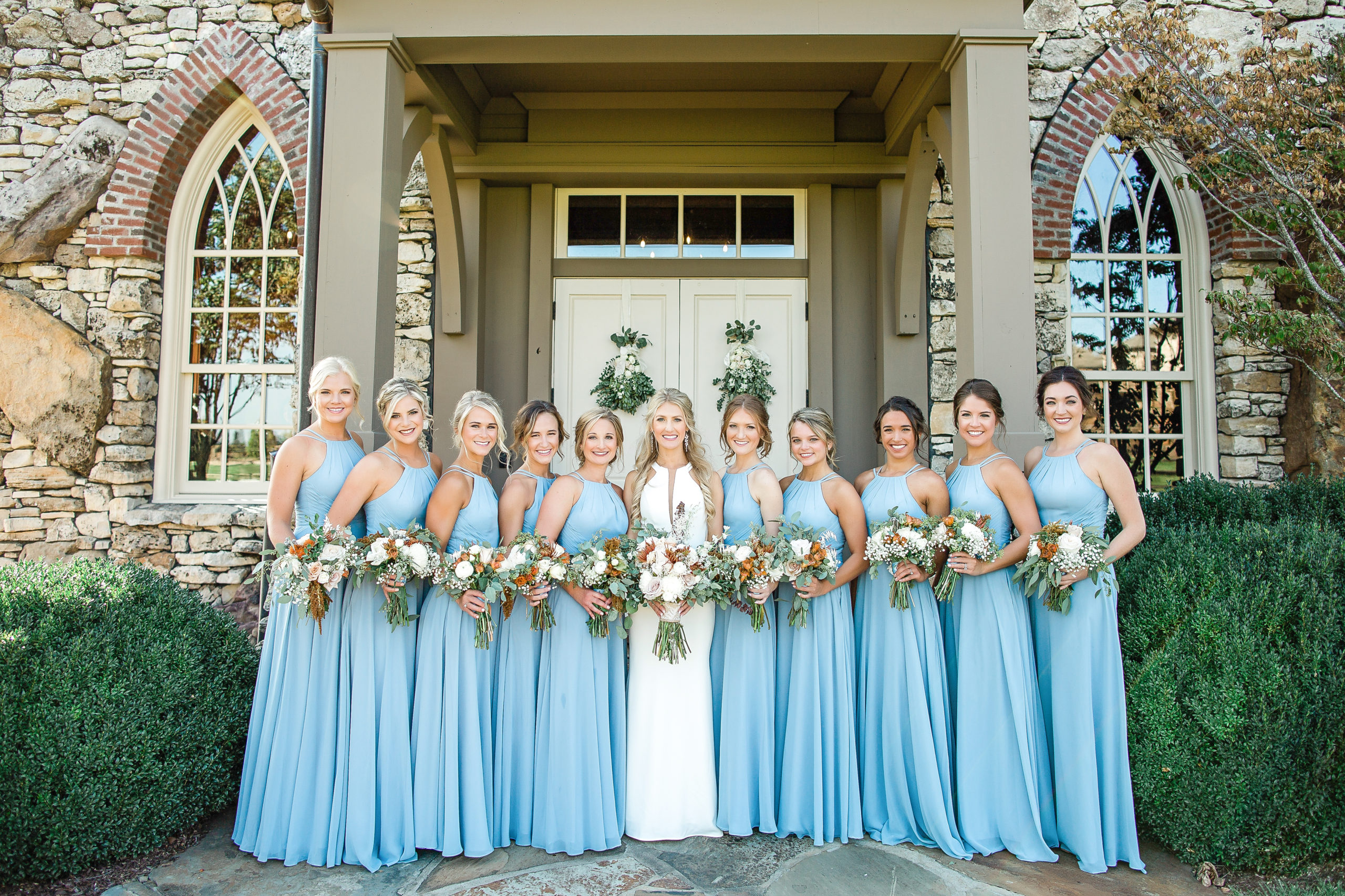 Bride and her bridesmaids with a closeup of their bouquet details in front of the Chapel of the Ozarks at Top of the Rock