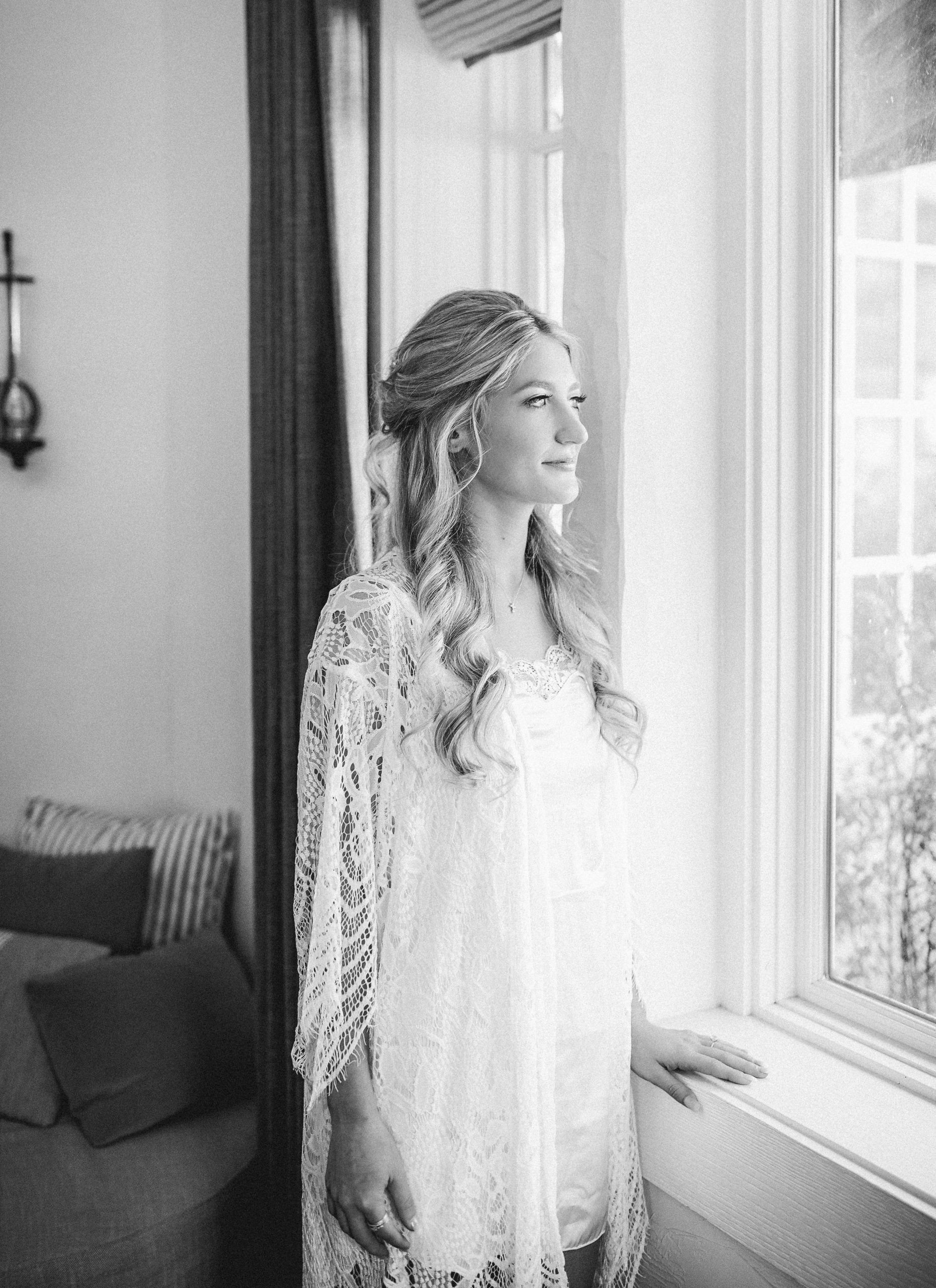 Bride looking out the window in black in white in her getting ready robe at Big Cedar Branson, MO by Tatyana Zadorin Photography