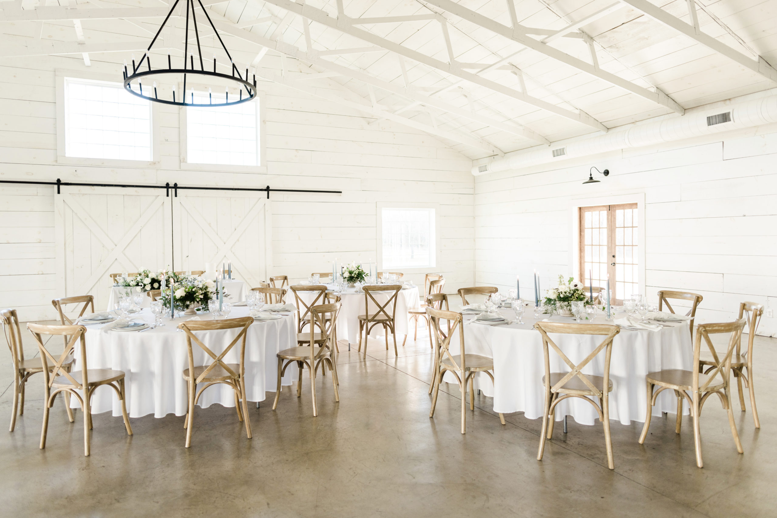 Round tables set up at the wedding reception venue with at timeless and classic decoration and a chandelier overhead shot by natural light photographer Tatyana Zadorin Photography