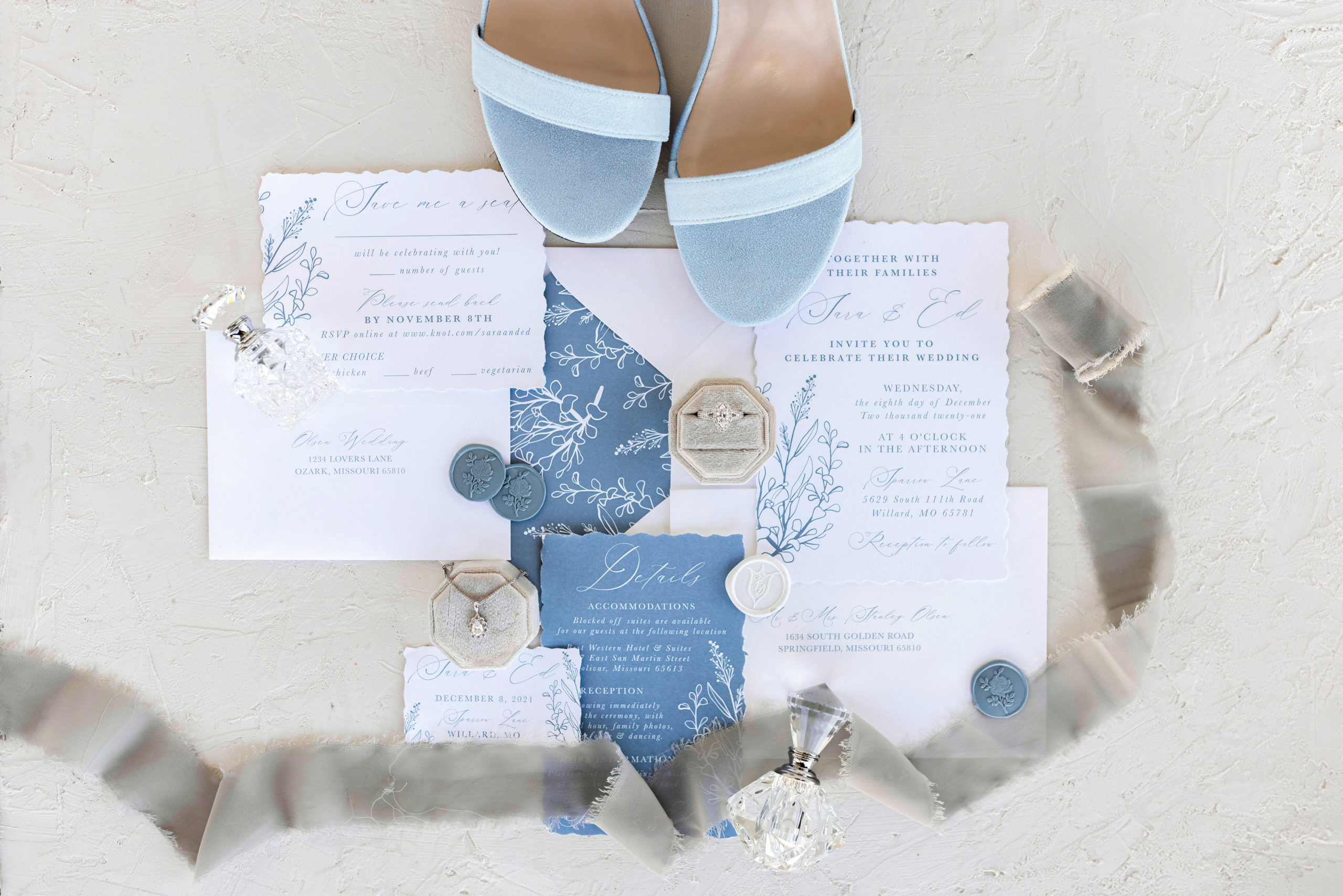 Flat-lay shot of the light blue themed wedding invites and stationary with her shoes and accessories