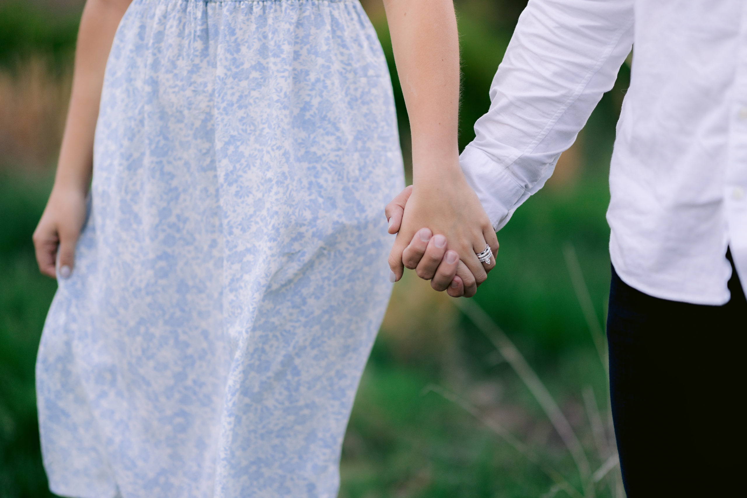 Close-up shot of couple holding hands showing ring on woman's finger for their spring engagement photos, shot by fine art wedding photographer Tatyana Zadorin