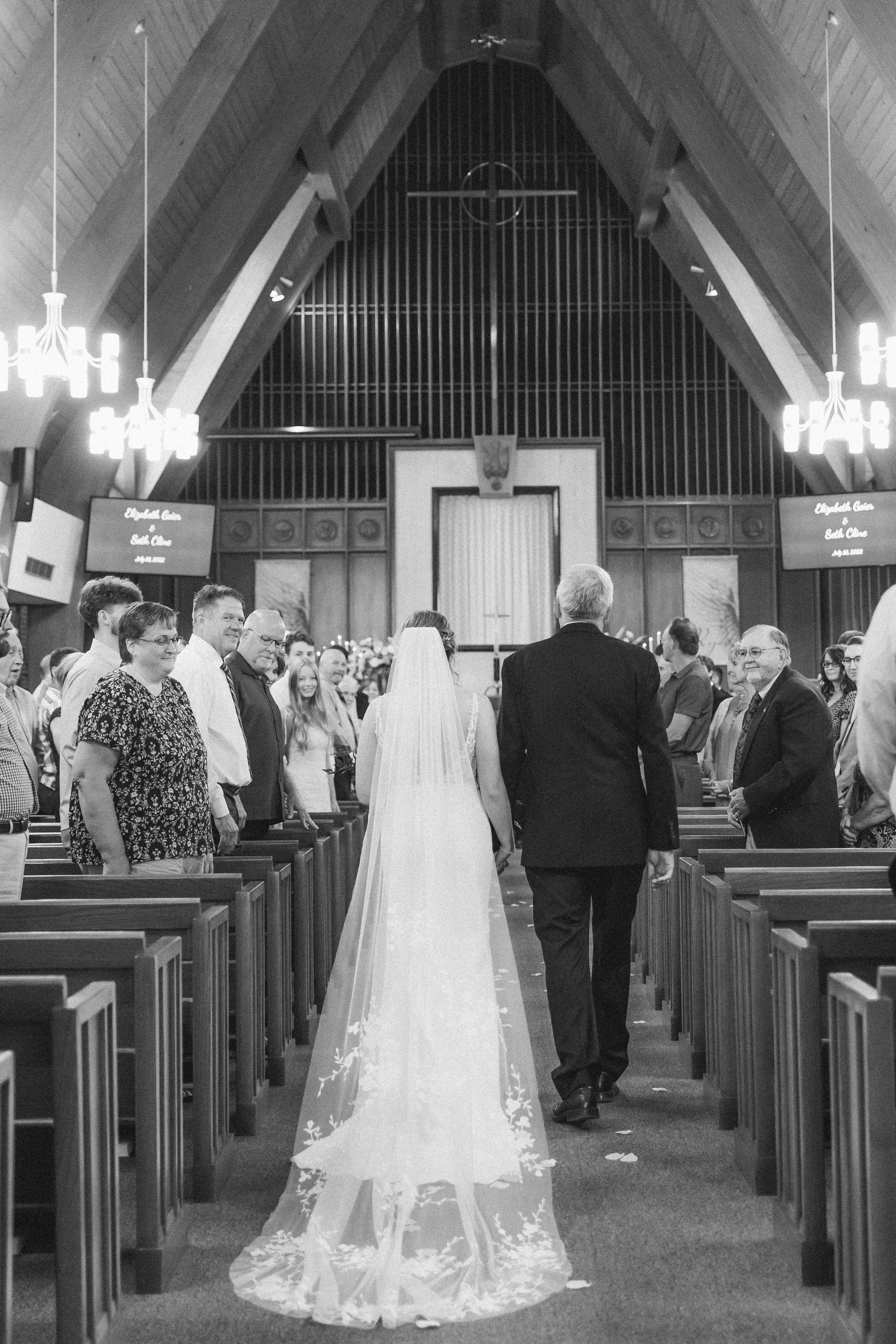 Bride walking down the isle with her father at a catholic church