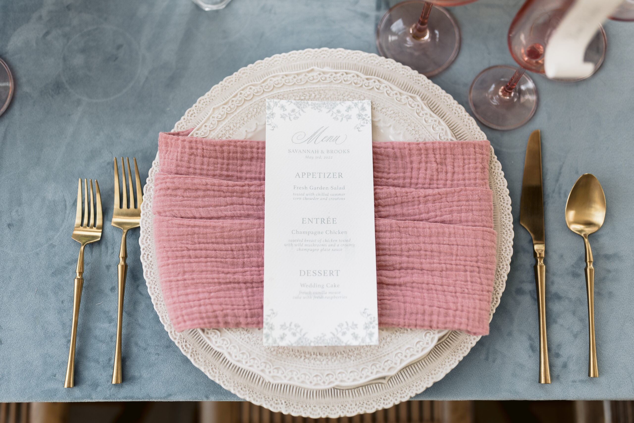 Flat-lay shot of menu planed on pink napkin and plates with gold utensils, shot by fine art wedding photographer Tatyana Zadorin