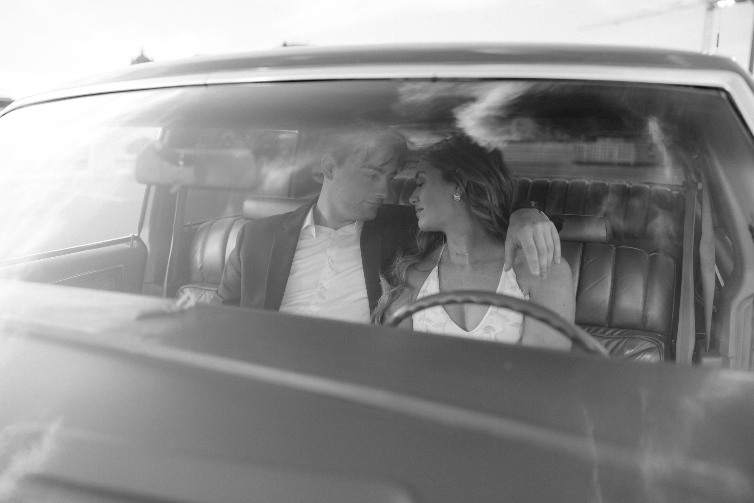 black and white engagement portrait inside a vintage car of a couple