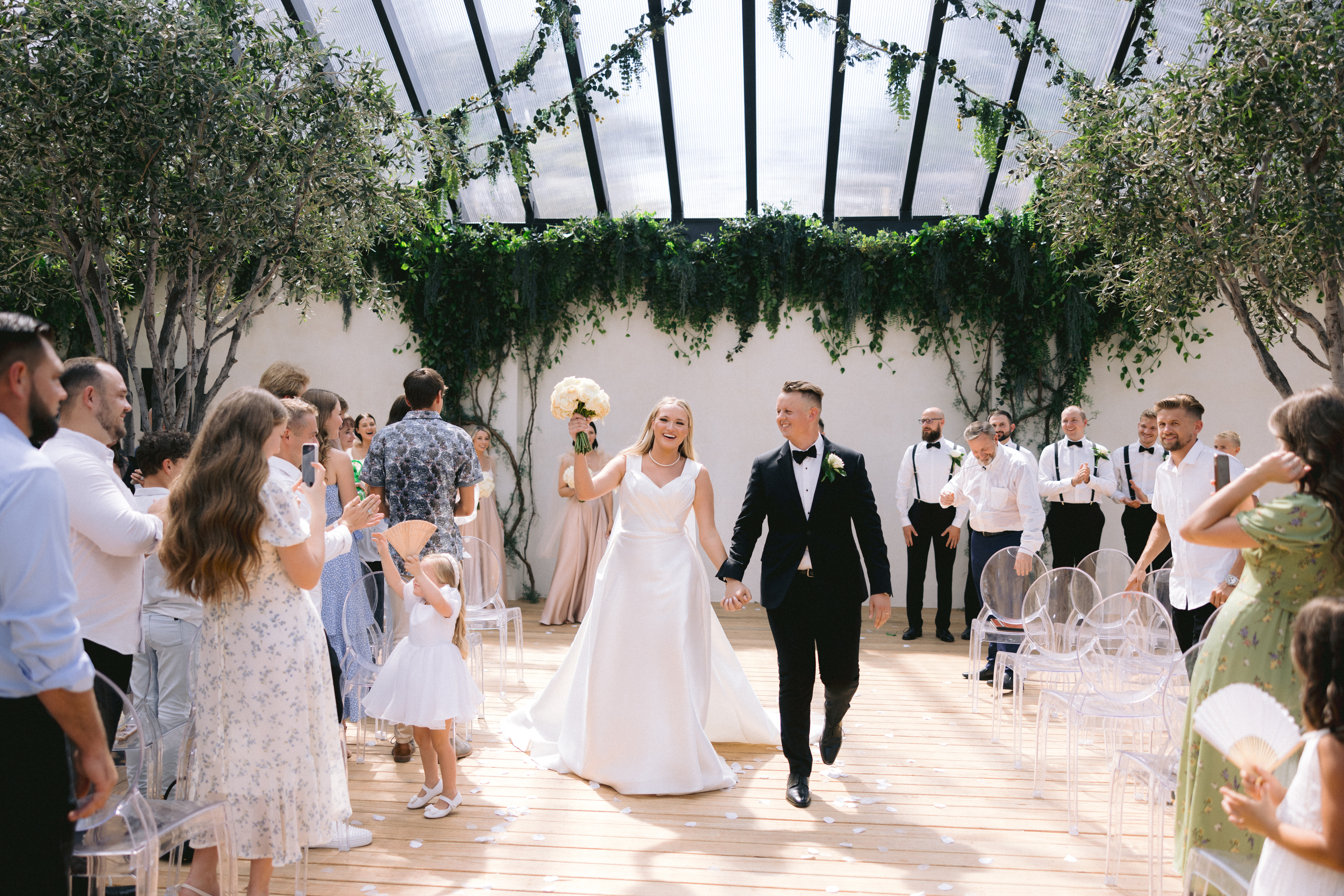 Bride and groom walking down the isle cheering at the Greenhouse Two Rivers wedding