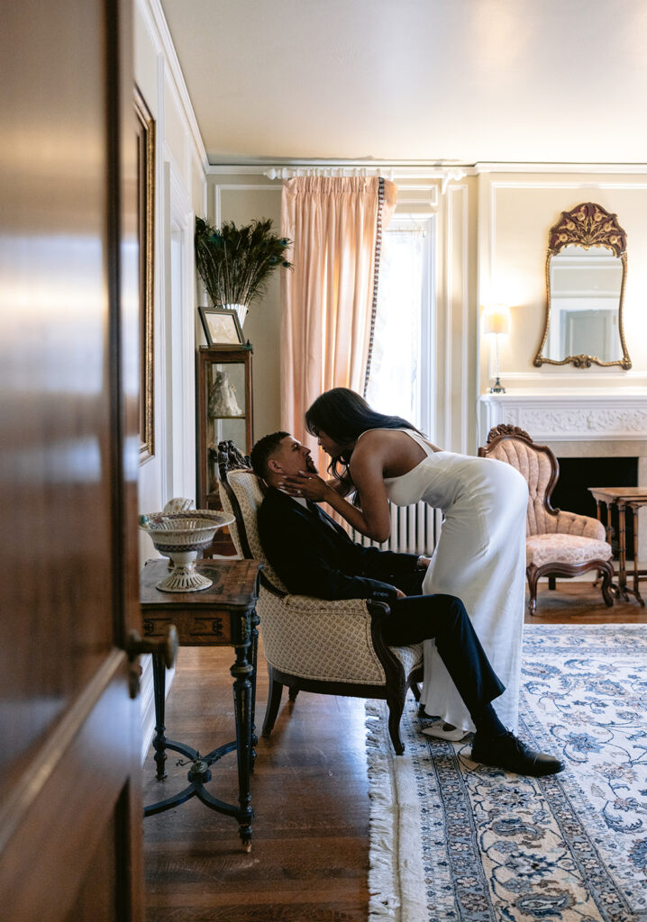 Editorial engagement photo of a couple sharing a romantic kiss inside a historic room at the Aldredge House in Dallas.