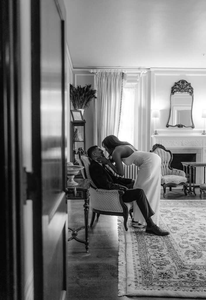 Elegant black-and-white engagement photo of a couple sharing a quiet moment inside the historic Aldredge House mansion.