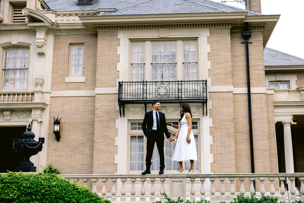Luxury engagement portrait of a couple standing together outside the grand entrance of the Aldredge House in Dallas, Texas.