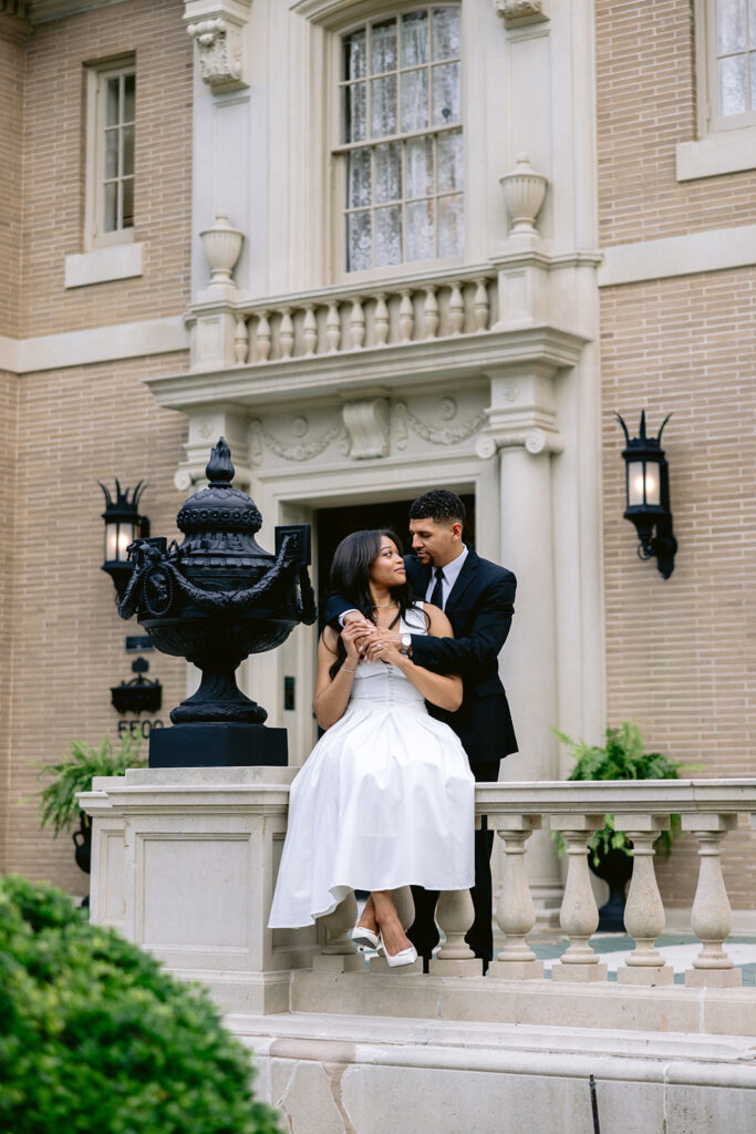 Romantic engagement portrait of a couple embracing on the front steps of the historic Aldredge House in Dallas, Texas.