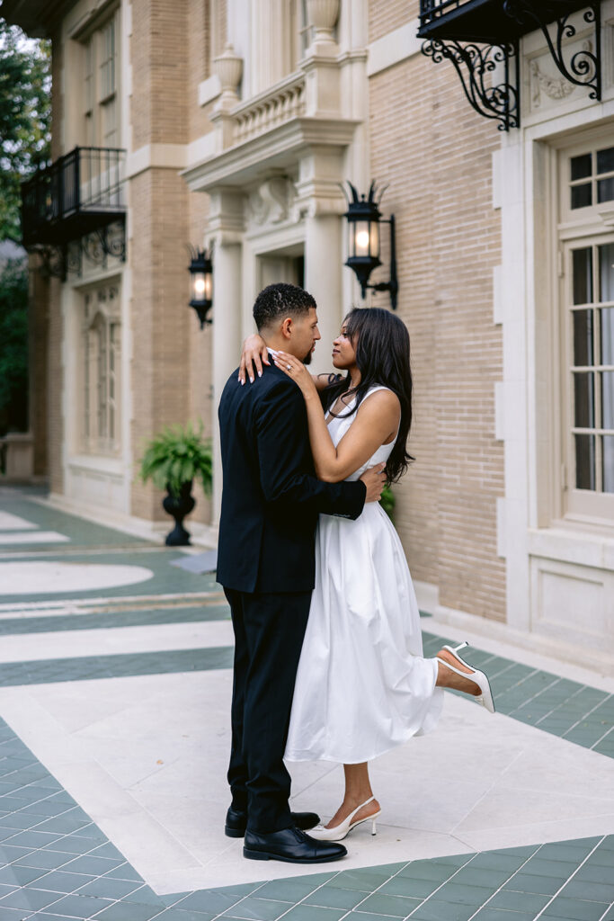 Timeless engagement portrait of a couple embracing in the courtyard of the historic Aldredge House during their Dallas engagement session.
