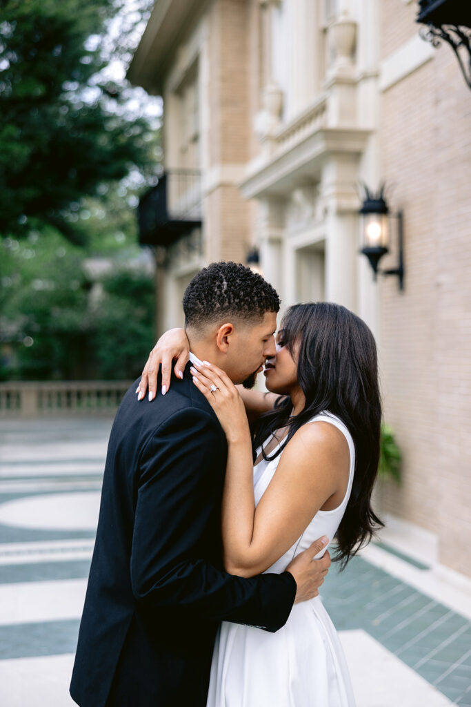 Intimate engagement portrait of a couple sharing a kiss outside the Aldredge House in Dallas, Texas.