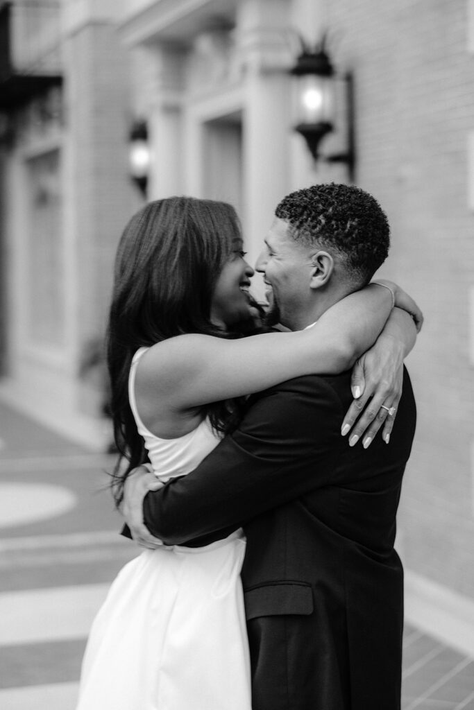 Timeless black-and-white engagement portrait of a couple embracing outside the historic Aldredge House in Dallas, Texas.