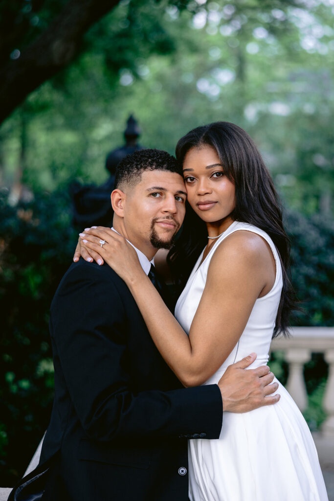 Elegant engagement portrait of a couple embracing beneath lush green trees during their Aldredge House engagement session.
