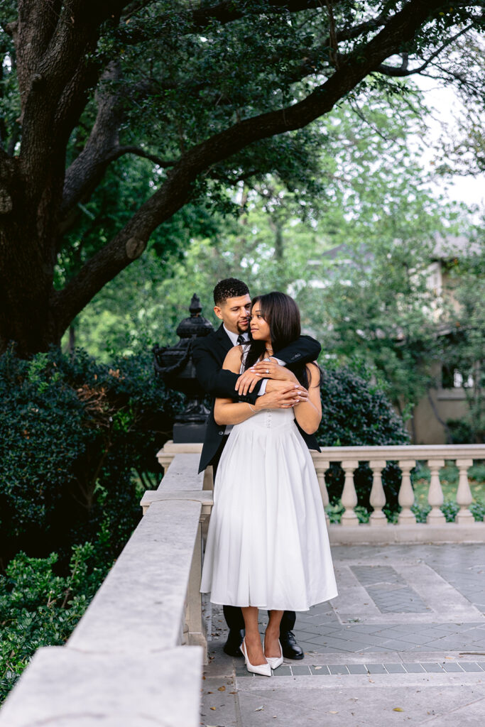 Romantic embrace beneath mature oak trees during an elegant engagement session at the Aldredge House in Dallas.