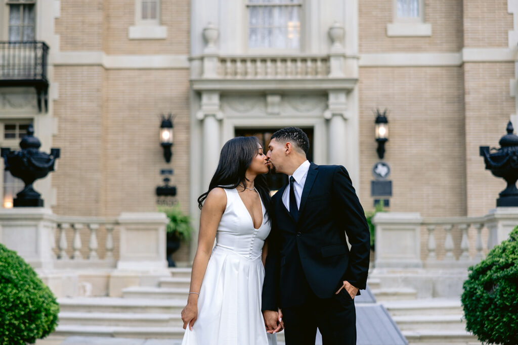 Close-up engagement portrait of a couple sharing a kiss in front of the historic Aldredge House mansion.