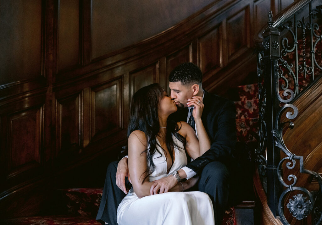 Elegant engagement photo of a couple sharing an intimate moment on the staircase of the Aldredge House mansion.