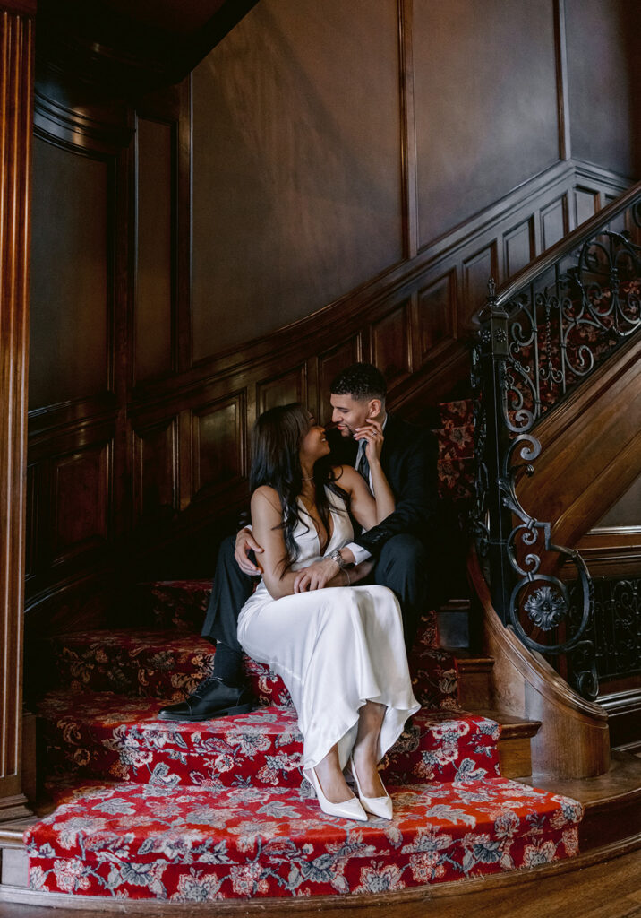 Luxury engagement portrait of a couple embracing on the ornate staircase inside the historic Aldredge House.