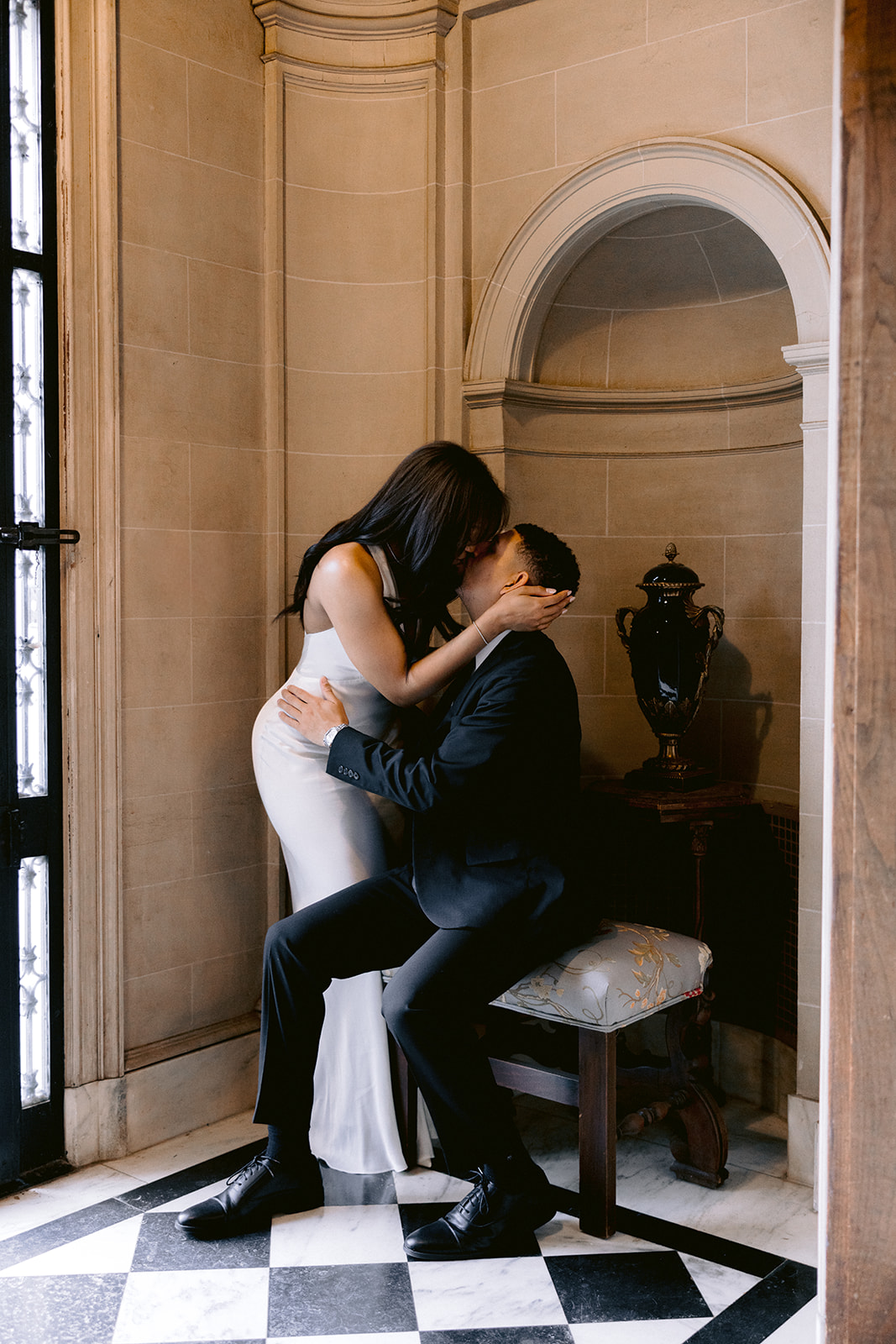 Luxury engagement portrait of a couple kissing in the grand arched entryway of the historic Aldredge House in Dallas, Texas.
