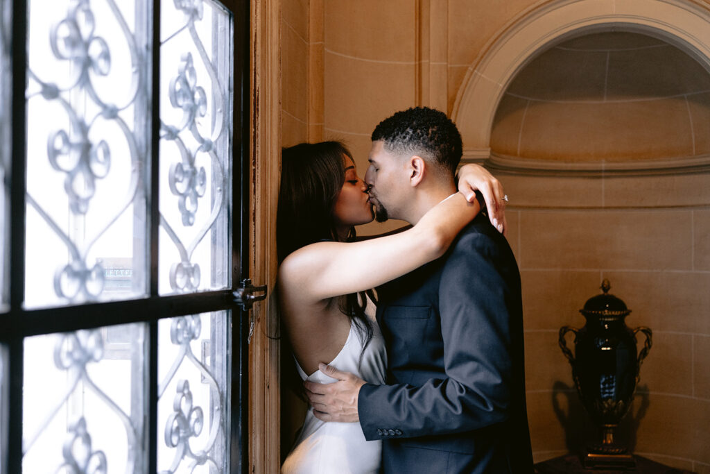 Romantic engagement photo of a couple kissing in a doorway inside the historic Aldredge House in Dallas, Texas.