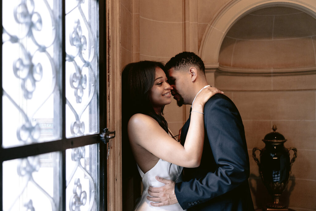 Close-up engagement portrait of a smiling couple embracing in the historic doorway of the Aldredge House in Dallas.