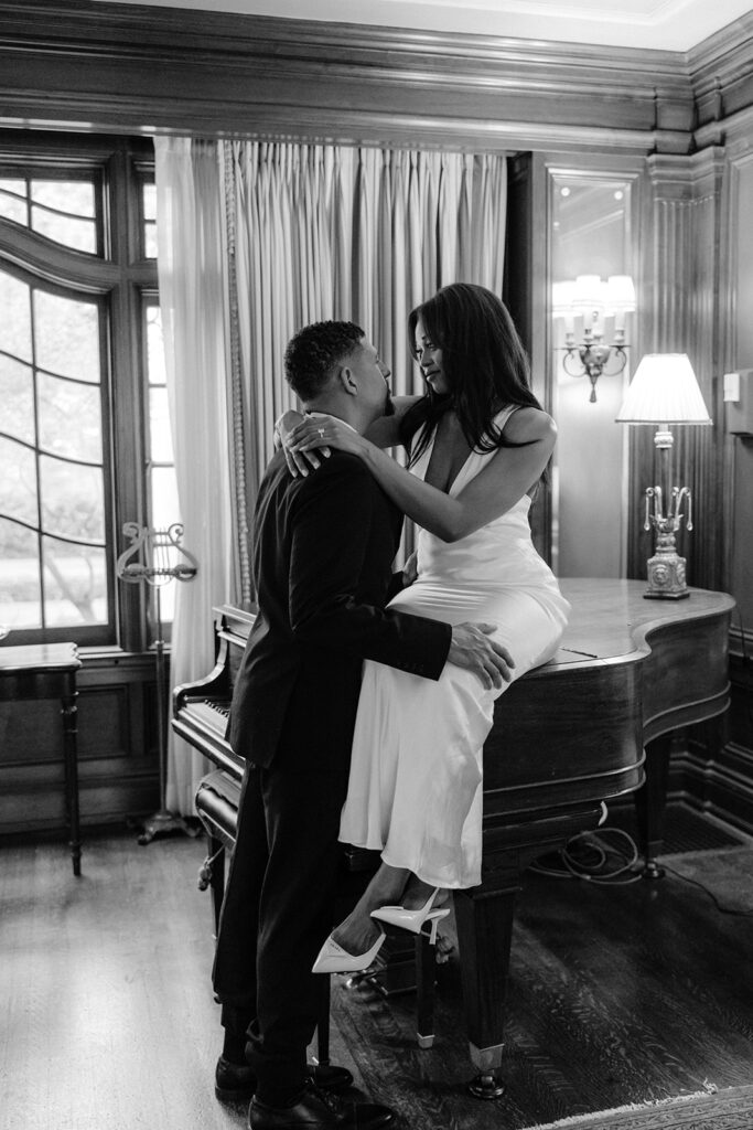 Luxury engagement portrait of a couple creating intimate editorial-style portraits around a grand piano inside the historic Aldredge House.