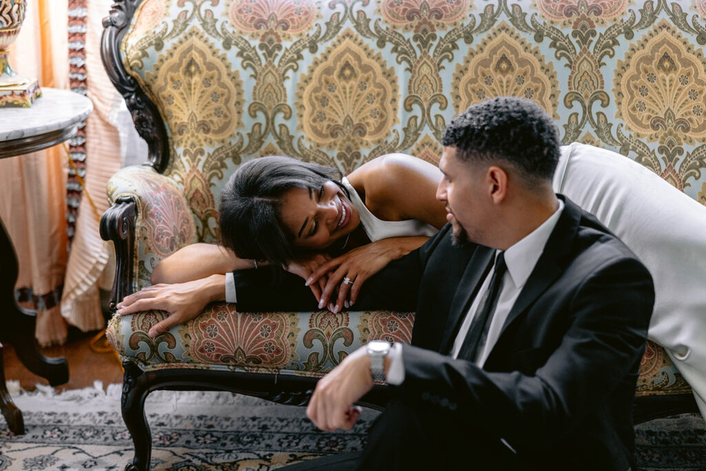Romantic indoor engagement photo of a couple sharing a quiet moment on a vintage sofa inside the Aldredge House in Dallas, Texas.