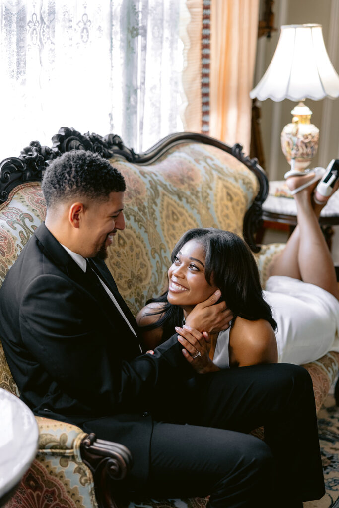 Elegant engagement portrait of a groom gently holding his fiancée's face as they share a romantic moment indoors.