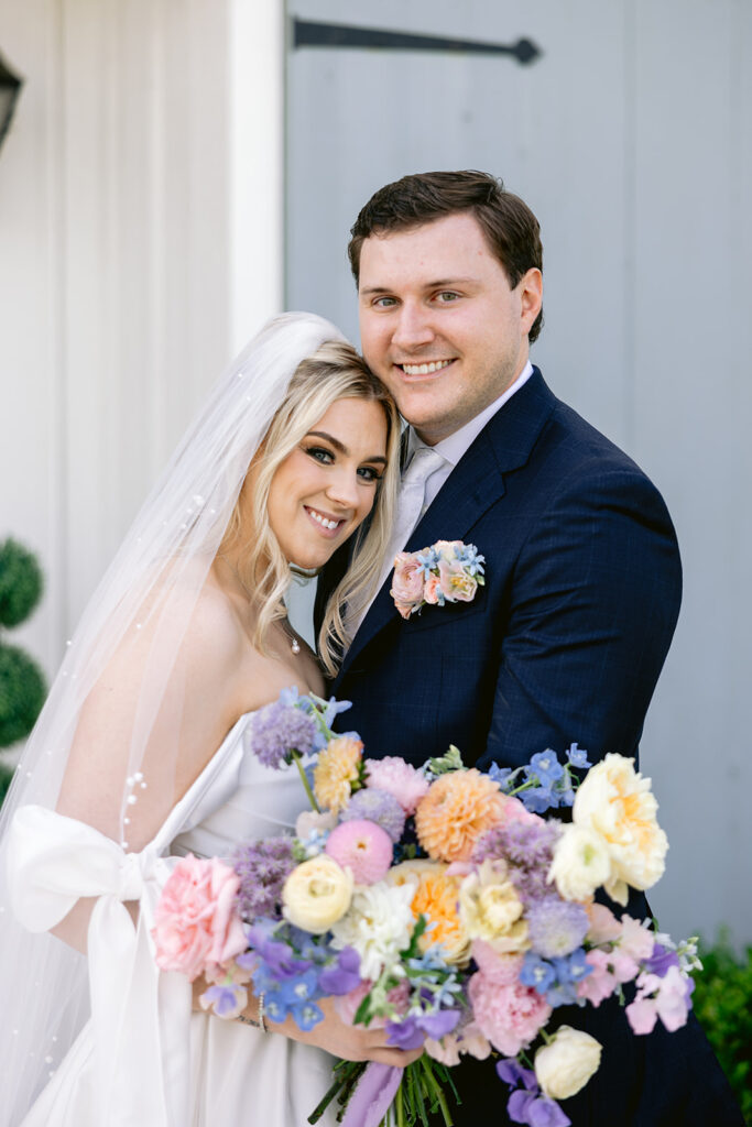 Timeless bride and groom wedding portraits featuring a colorful pastel bridal bouquet, romantic embraces, elegant veil details, and joyful newlywed moments at The French Farmhouse wedding venue in Collinsville, Texas.