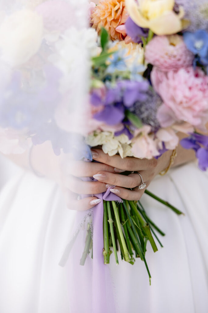 Elegant bridal portraits featuring the bride holding a colorful pastel wedding bouquet, flowing cathedral veil, timeless wedding gown, and romantic outdoor portraits at The French Farmhouse wedding venue in Collinsville, Texas.