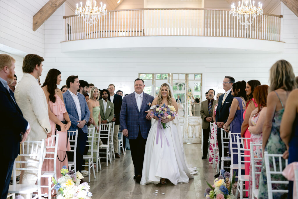 Emotional wedding ceremony featuring the bride walking down the aisle with her father, heartfelt ceremony moments, the bride and groom exchanging vows, and joyful reactions inside the bright chapel at The French Farmhouse wedding venue in Collinsville, Texas.