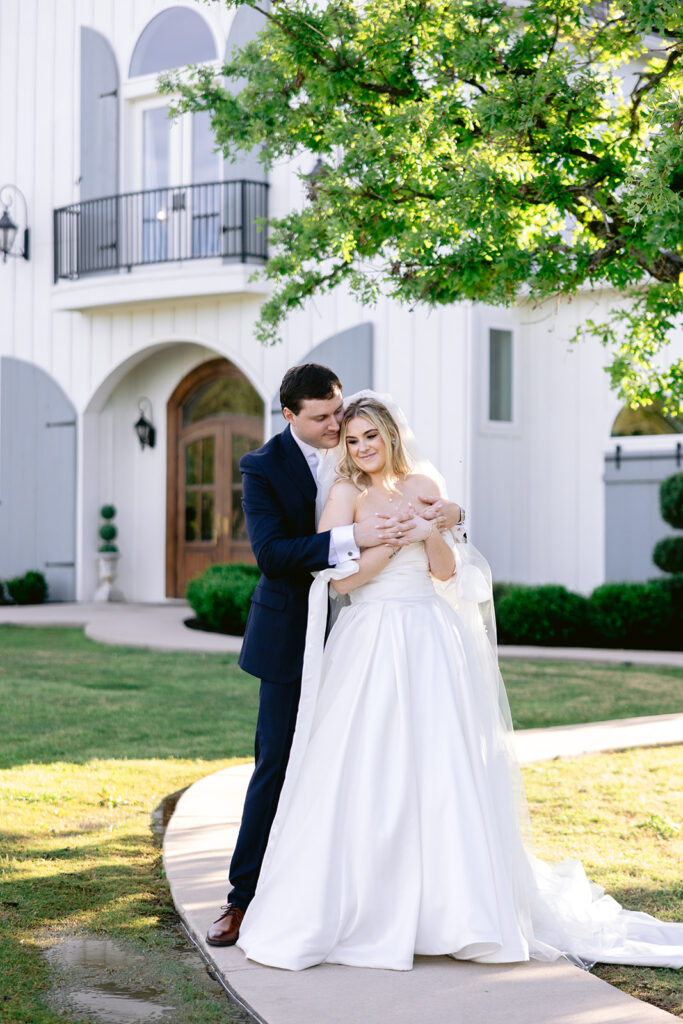 Romantic newlywed portraits featuring the bride and groom embracing, holding hands with wedding rings on display, sharing intimate kisses, and elegant outdoor wedding portraits at The French Farmhouse wedding venue in Collinsville, Texas.